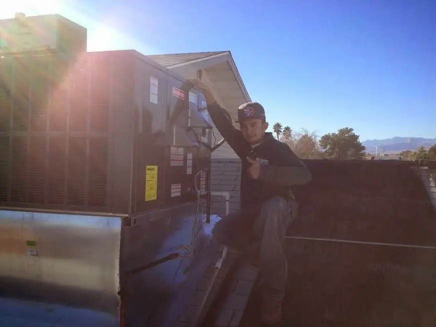 HVAC technician performing Air Duct Repair on a rooftop unit in Grants